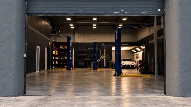 The Custom Auto Care garage door open, with two lifts and a white Toyota Supra in the back bay